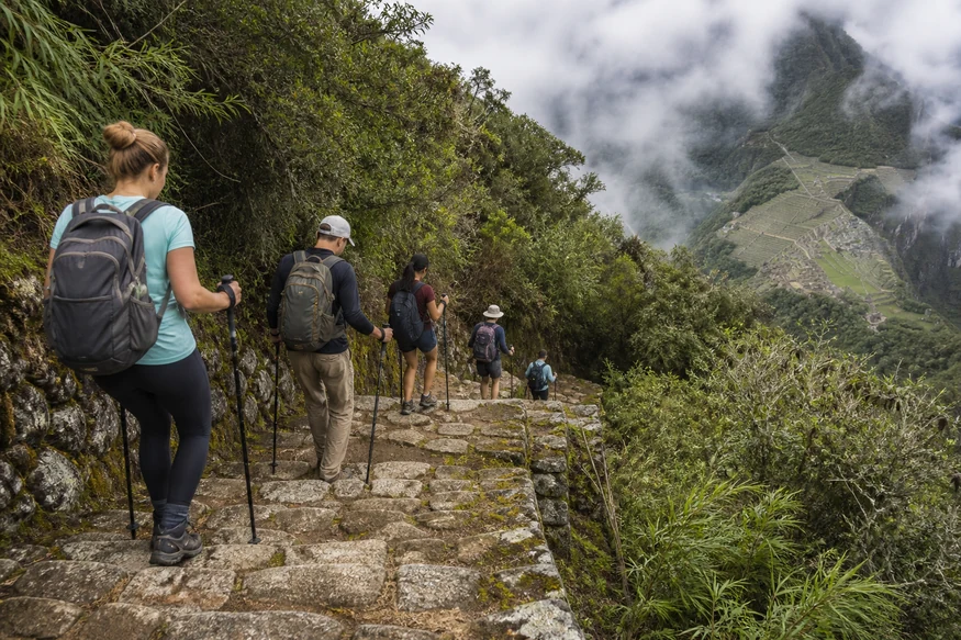 Travelers descending uneven stone steps on the Inca Trail