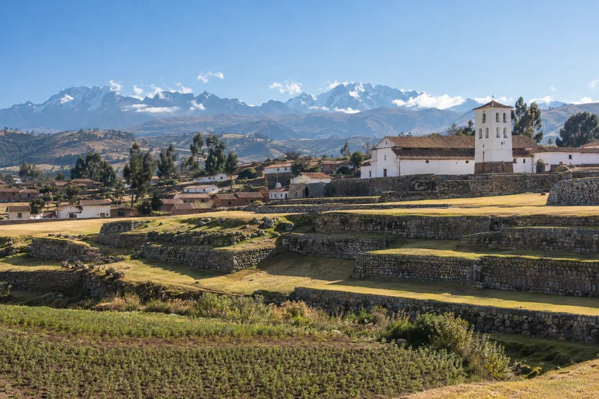 Panoramic view of Chinchero's Inca terraces, historic church and Andean mountains in Peru