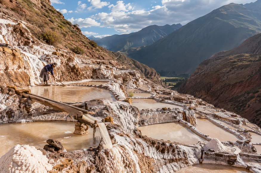 Local salt worker tending traditional evaporation ponds at Maras Salt Mines