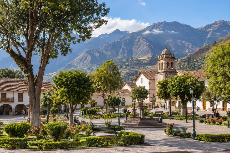 Tree-lined town plaza in Urubamba Peru with Andean mountains in the background